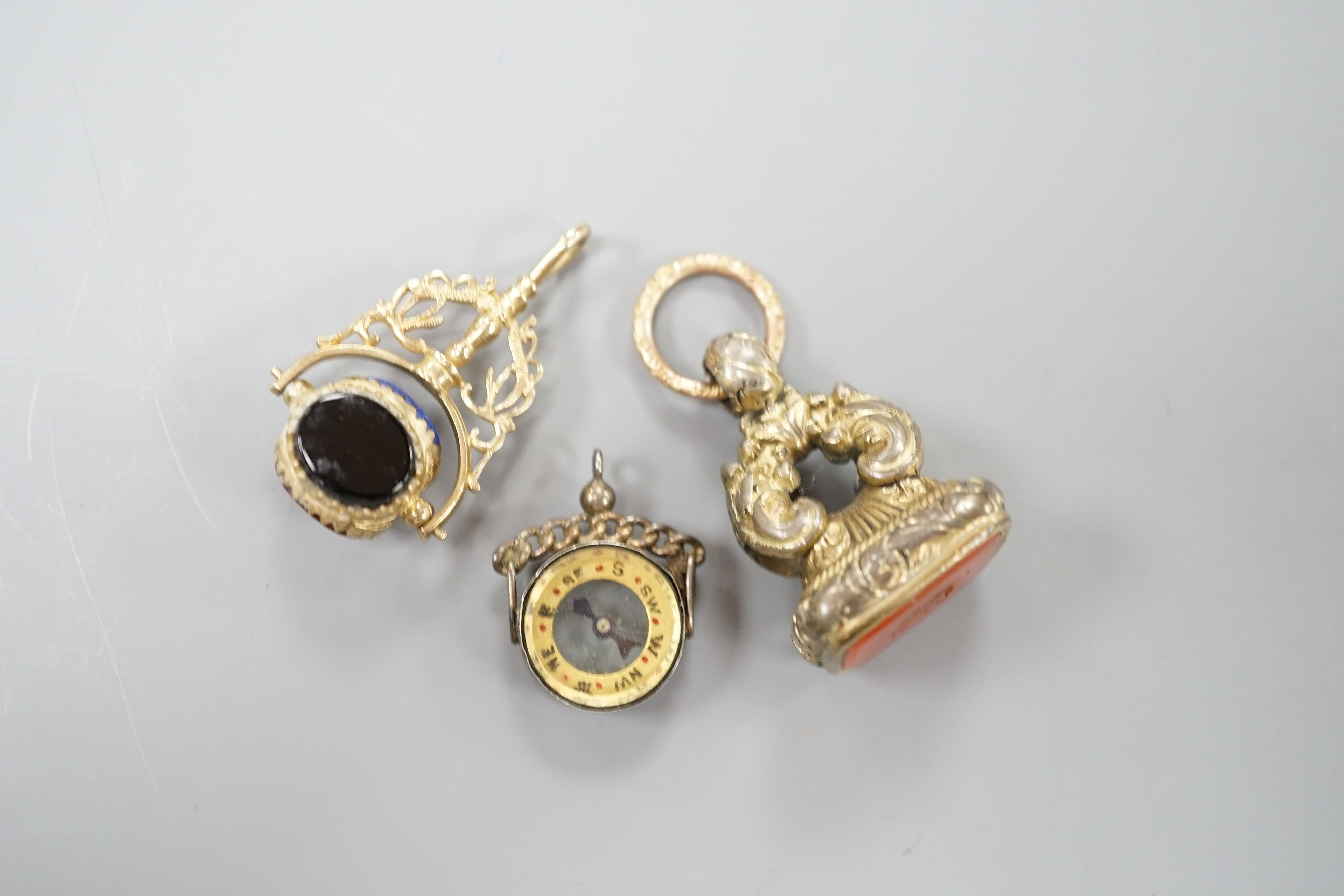 A modern 9ct gold and carnelian set swivelling fob seal, 40mm, a Victorian gold plated and carnelian set fob seal and a white metal mounted (stamped silver) compass fob.